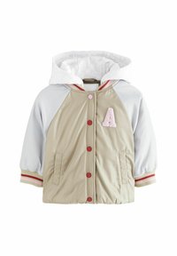 Lätt jacka i beige och grått, med en huva, röda knappar, elastiska ärmslut och en rosa bokstav "A"-patch. Slätt, vattentåligt tyg.