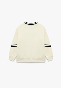 Crèmekleurige sweatshirt met een zwarte gestreept geribbelde kraag en manchetten, met verlaagde schouders en een ontspannen pasvorm ontwerp.