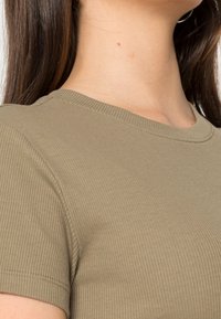 T-shirt a coste verde oliva con colletto rotondo e maniche corte, caratterizzata da una texture sottile e un design attillato.