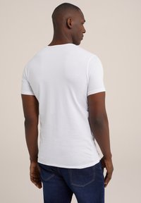 Witte kortemouw t-shirt met een ronde hals, gemaakt van zachte stof, met een gladde textuur en een getailleerd ontwerp, gecombineerd met donkerblauwe jeans.