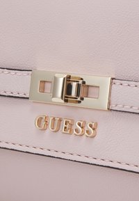 Borsa in ecopelle rosa con accessori in oro, dotata di una chiusura rettangolare e logo del marchio impresso. Dettagliamo cucito lungo i bordi.