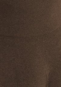 Bruine leggings met een textuur van ribstof en een gladde afwerking, ontworpen voor comfort en flexibiliteit in de pasvorm.