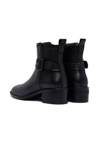 Bottes noires en cuir à talons, avec un bout arrondi, un talon, une finition en boucle et des détails de couture. Comprend des languettes pour un enfilage facile.