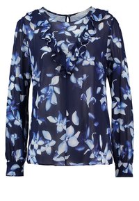 Marineblå bluse med blomstret print i blå og hvid. Lange ærmer, rynket halsudskæring, blødt, gennemsigtigt stof og knaplukning bagpå.