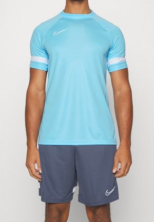 T-shirt de sport bleu à manches courtes, accents blancs, col rond et logo Nike sur la poitrine gauche, associé à un short gris foncé.