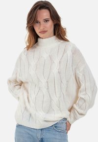 Pullover mit Zopfmuster in Creme, mit hohem Kragen und lockerem Sitz. Weiche Textur mit filigranen Musterdetails sowie gerippten Bündchen und Saum.