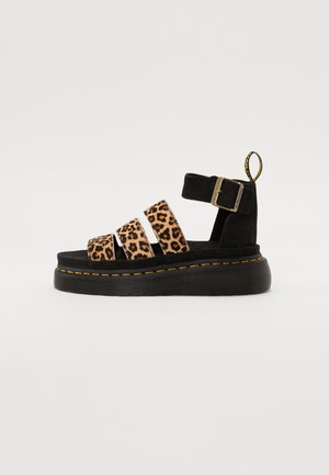 Sort platformsandal med tre leopardmønstrede remme, spænde omkring anklen og gule stikninger på sålen mod en hvid baggrund.