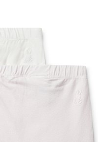 Dva páry legín, jedny bílé a jedny světle růžové, obě s vyraženým motivem králíčka poblíž pasu a jemnou texturou.