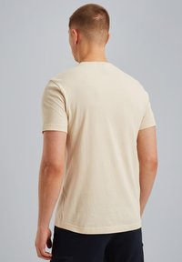 Harmaa puuvillainen t-paita lyhyillä hihoilla, pyöreällä kaula-aukolla ja suoralinjaisella helmalla. Minimalistinen muotoilu, jossa on sileä ja pehmeä rakenne.