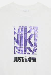 White sweatshirt featuring a bold purple graphic of the word "NIKE" and the slogan "JUST DO IT." Textured print with geometric elements.