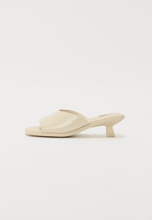 Mules beiges à enfiler avec un dessus en polyuréthane lisse et brillant, bout ouvert et un petit talon carré.