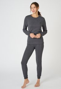 Sudadera gris y pantalones ajustados a juego de tejido suave. Presenta un cuello redondo, puños acanalados y un sutil detalle de logotipo en el pecho.