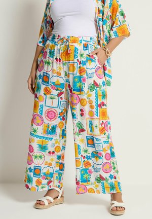 Bukser med vide ben og farverige tropiske motiver, herunder solen, frugter, palmer og sejlbåde, kombineret med hvide sandaler og matchende skjorte.
