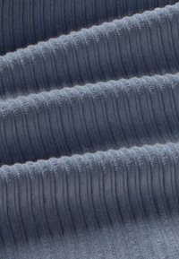 Grijs ribbelstof met een licht gestructureerd oppervlak met evenwijdige ribbels, die zachte plooien en een subtiele glans tonen.
