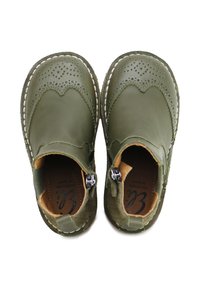 Zapatos de cuero verde con detalles de brogue, paneles laterales elásticos, cierre de cremallera y plantillas contrastantes en color marrón claro. Costuras visibles a lo largo de los bordes.