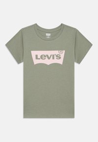 Ελαιόχρωμο βαμβακερό μπλουζάκι με μεγάλο ροζ λογότυπο Levi's σε χαρακτηριστικό καμπύλο σχέδιο. Κοντά μανίκια και στρογγυλή λαιμόκοψη.