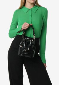 Borsa a secchiello nera in finta pelle con stampa coccodrillo, con finitura testurizzata, hardware dorato e manico intrecciato. La borsa ha una chiusura con coulisse.