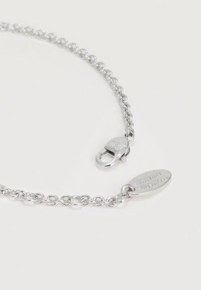 Colier cu lanț argintiu cu verigi rotunde, închizătoare lobster și etichetă ovală mică gravată cu numele mărcii pe un fundal deschis.