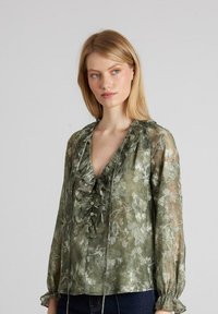 Durchsichtige grüne Bluse mit blumigem Muster, Rüschenausschnitt, Knöpfen und langen Puffärmeln. Zarte Textur aus einem weichen, leichten Stoff.