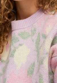 Pull à motif floral avec des couleurs pastel, principalement lavande et jaune. Confectionné en maille douce et texturée avec un col rond.