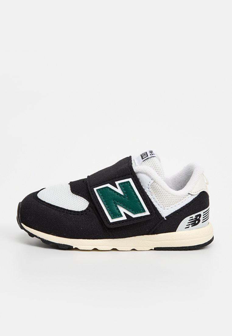 Baskets noir et blanc avec des matériaux en maille et en daim, présentant un logo "N" vert, une sangle réglable et une semelle beige.
