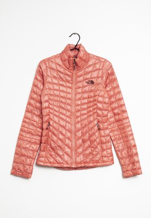 Hellkorallen gesteppte Jacke mit Frontreißverschluss und seitlichen Reißverschlusstaschen, hängt an einem schwarzen Kleiderbügel, Logo auf der linken Brust.