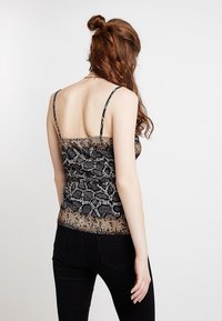 Top senza maniche in stampa serpente nero e marrone, con bretelle sottili, design aderente e tessuto strutturato, caratterizzato da arricciature sul retro.