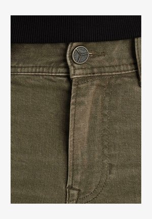 Olijfgroene denim jeans met een gestructureerde afwerking, voorzien van een zilveren knoop en contrasterende stiksels langs de tailleband en het zakgebied.