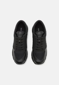 Scarpe da ginnastica nere con una combinazione di pelle liscia e superiore in rete, dotate di sei fori per i lacci e suole in gomma per supporto e grip.