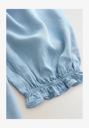 Gaiši zils, viegls audums ar mīkstu tekstūru; ar savilktu elastīgu apakšmalu ar frēzējumu. Gluda, nedaudz krunkaina izskats.