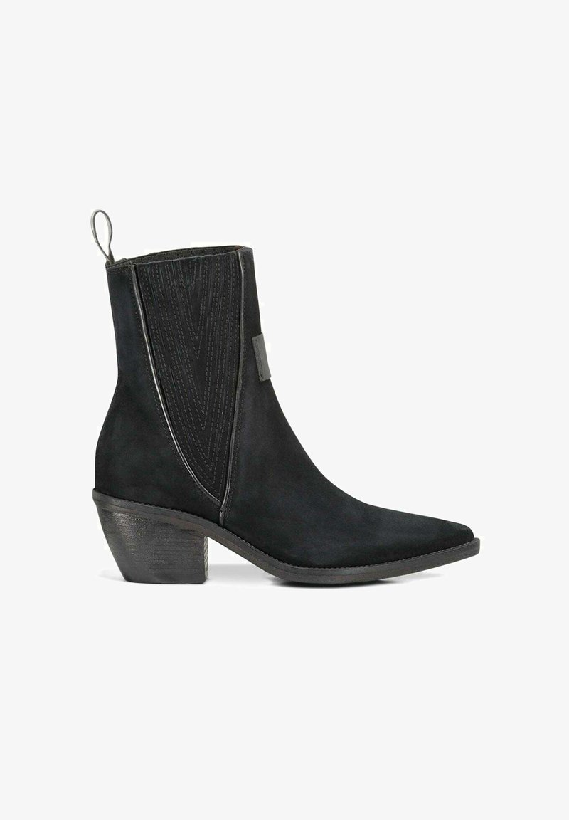 Zwarte suède enkellaars met spitse neus, voorzien van verticale stiksels en een korte, stevige hak. Lussen voor gemakkelijk aan- en uittrekken.