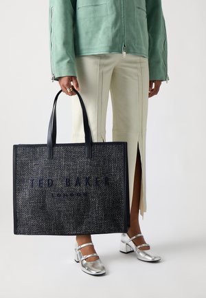Marineblauwe stoffen tas met een geëmbosséeerd ontwerp, het logo "TED BAKER LONDON" en dubbele zwarte handvatten.