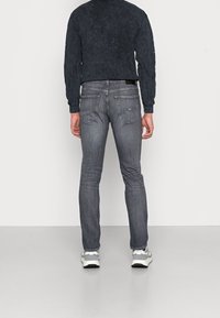 Grå denimjeans med smal passform, som har fem fickor och subtila sömnadsdetaljer. Matchas med en svart strukturerad långärmad topp och sneakers.