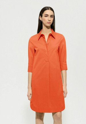 Kragenkleid in leuchtendem Orange, aus glattem Baumwollstoff. Mit Dreiviertelärmeln und einem lockeren Schnitt, der knapp über dem Knie endet.