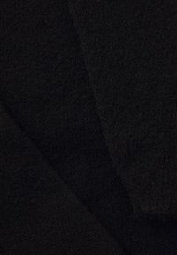 Schwarzer Stoff, weiche Textur, leicht flauschiges Aussehen, zeigt überlappende Stücke in unterschiedlichen Schattierungen von dunkel Schwarz.