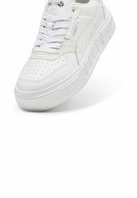 Sneaker in pelle bianca con punta perforata, lacci e suola in gomma rialzata. Presenta una marca laterale e un design a texture liscia.