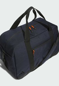 Navy blue duffel bag with black straps, two orange zipper pulls, and a side pocket. Textured fabric, sturdy construction, and branding on end.