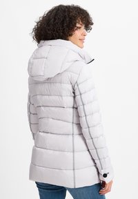 Lichtgrijze pufferjack met een capuchon, voorzien van een gequiltde textuur en zwarte accenten op de manchet en de ritsen. Aansluitende pasvorm met een iets uitlopende zoom.