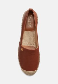 Brown leather espadrille with woven jute sole. Features a flat design, textured surface, and subtle branding in gold on the side.