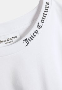 Valge puuvillast t-särk, millel on musta "Juicy Couture" kirjaga soonikkoes ümarsuu kaelus. Siseõmbluses on nähtav hooldusmärgis.