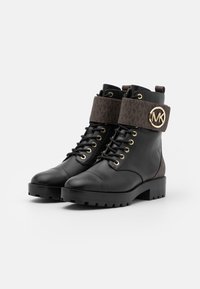 Sorte læder ankelstøvler med en brun mønstret manchet, guldfittings, snørebåndsdesign, rund tå og tyk sort sål.