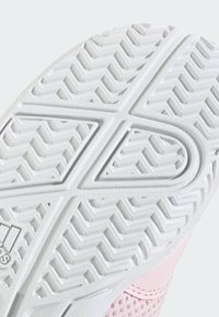 Semelle extérieure en caoutchouc blanc avec motif de profil en zigzag texturé et partie supérieure en mesh rose visible sur le bord.