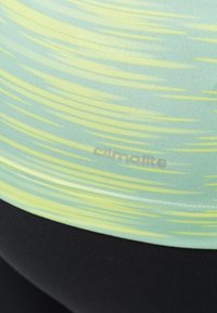 Jasnozielony i żółty wzorzysty top sportowy z teksturowanym wykończeniem, z logo "climalite" blisko dołu, zestawiony z czarnym materiałem.