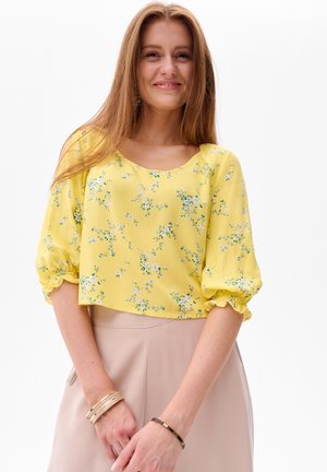 Geel cropped blouse met bloemenpatroon en elastische puffmouwen, met een ronde halslijn. Draag met een lichte rok.