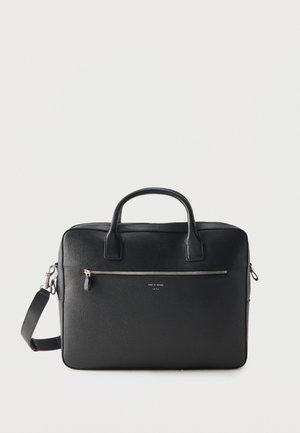 Czarna skórzana teczka z podwójnymi uchwytami, odpinanym paskiem na ramię, przednią kieszenią na zamek i małym tłoczonym tekstem marki na jednolitym tle.