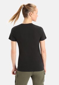 T-shirt in cotone nero con maniche corte, scollatura rotonda e design aderente. Il tessuto appare morbido con una consistenza liscia.