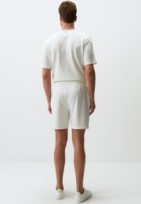 Top corto a maniche corte in cotone bianco e pantaloni short abbinati. Pantaloni short con vita elastica, texture liscia, design semplice e dettagli di cucitura minimi.