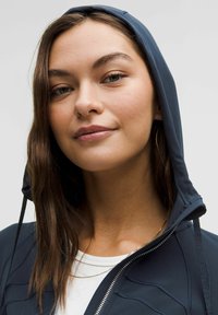 Jūras spēku zips hoody ar kapuci ar saites, struktūrētām paneļiem un redzamu balto iekšējo krekli. Gluda auduma un cieši pieguļoša dizaina.