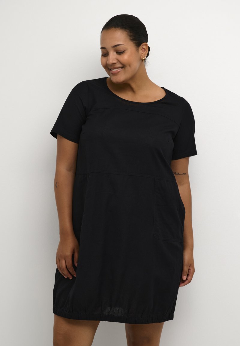 Schwarzes Kurzarmkleid mit rundem Ausschnitt, das einen gerafften Saum und zwei Seitentaschen bietet. Weicher Stoff mit lockerem Schnitt.
