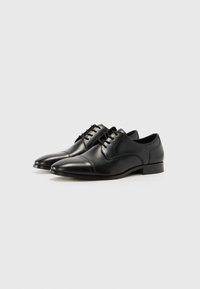 Zapatos de vestir de cuero negro con un acabado liso, punta afilada y diseño de cordones; presentan costuras sutiles y un tacón bajo.